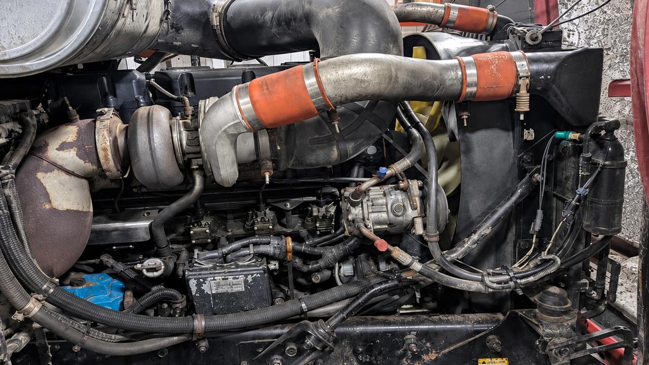 Close-up of a Mack diesel engine bay showing the turbo, orange coupler hoses, coolant hoses and radiator